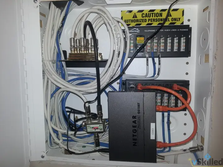 Netgear switch and network cabling inside a wall-mounted wiring cabinet